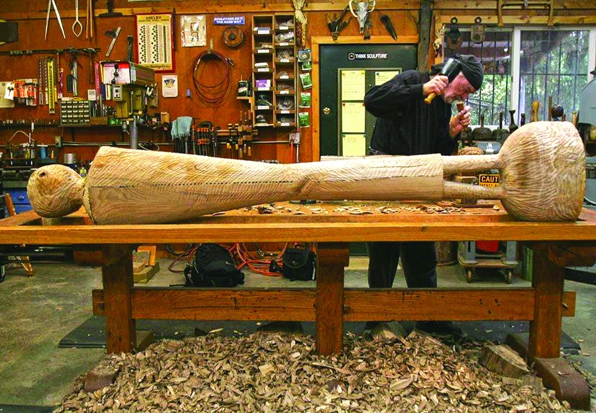 David Hostetler carving a reclining female wood sculpture in his studio