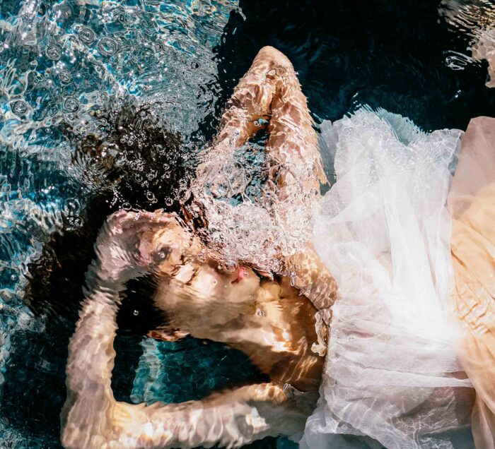 Underwater photograph of a figure in white tulle surrounded by bubbles